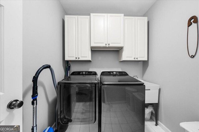 laundry room with separate washer and dryer, light tile patterned floors, and cabinets