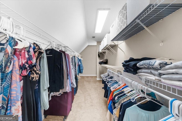 spacious closet featuring light colored carpet and vaulted ceiling