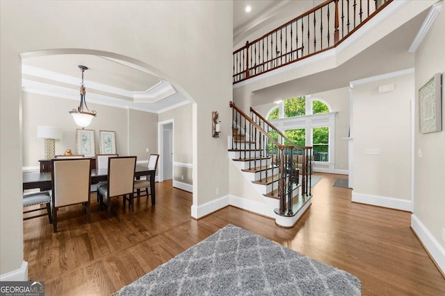 interior space with a raised ceiling, dark hardwood / wood-style flooring, ornamental molding, and a high ceiling