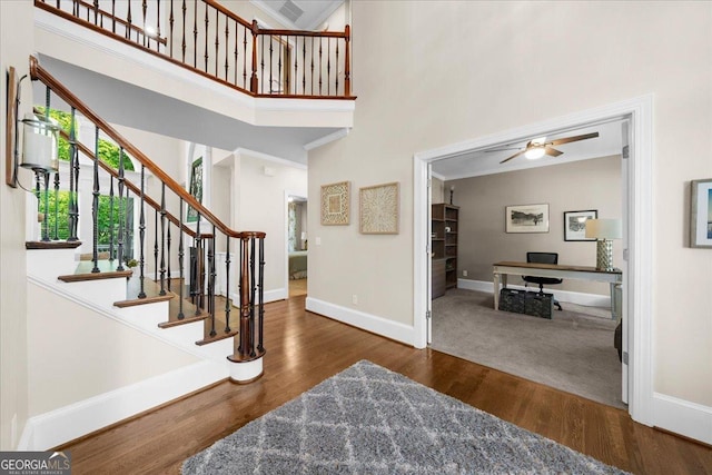 foyer with a high ceiling, dark hardwood / wood-style floors, ceiling fan, and crown molding