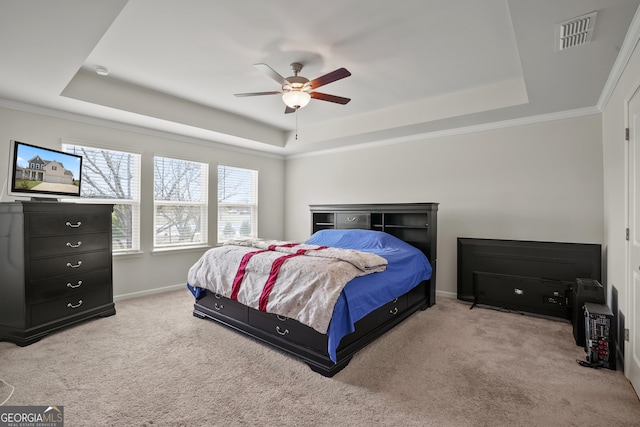 bedroom with ceiling fan, a tray ceiling, light carpet, and ornamental molding