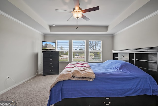 carpeted bedroom with ornamental molding, a tray ceiling, and ceiling fan