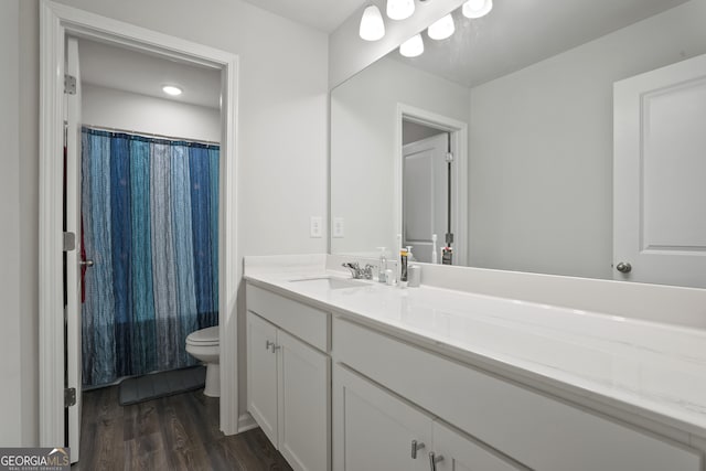 bathroom with wood-type flooring, vanity, and toilet