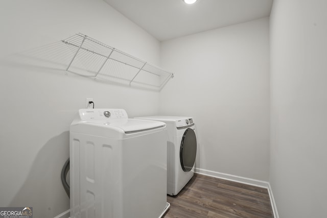 clothes washing area with washer and clothes dryer and dark hardwood / wood-style flooring