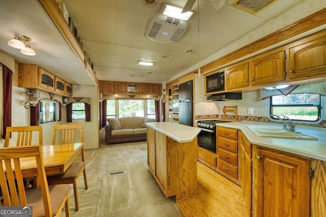 kitchen with light carpet, a wealth of natural light, black appliances, and a center island