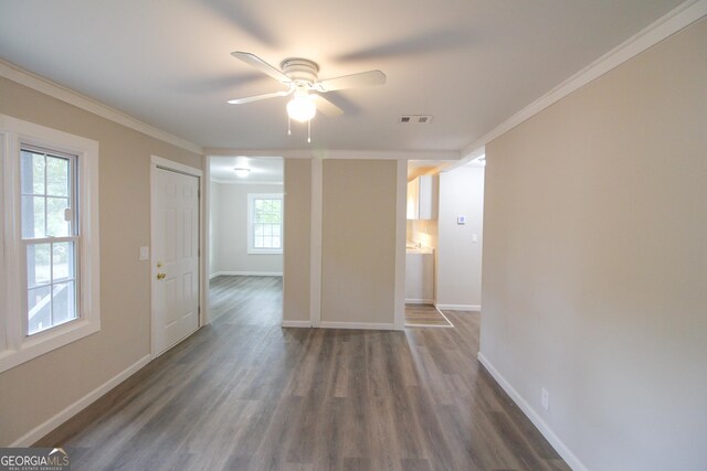 empty room featuring crown molding, ceiling fan, dark hardwood / wood-style flooring, and a healthy amount of sunlight