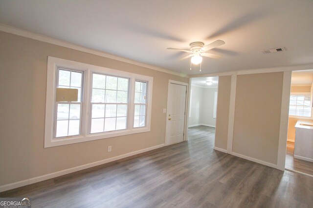 empty room featuring ceiling fan, crown molding, and dark wood-type flooring