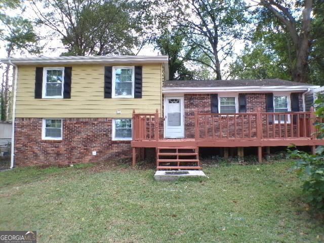 rear view of property featuring a yard and a deck