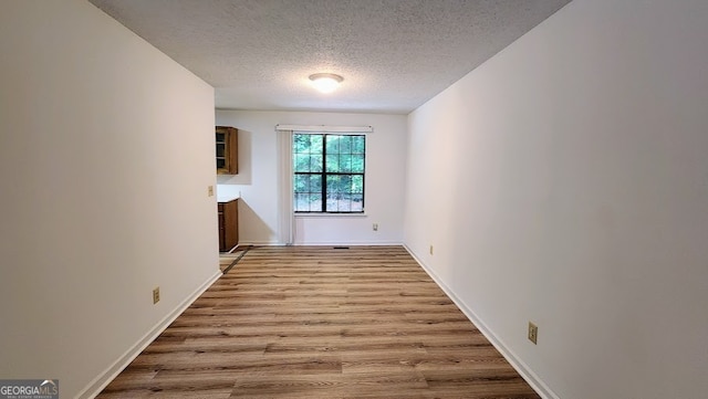 spare room with a textured ceiling and light hardwood / wood-style floors