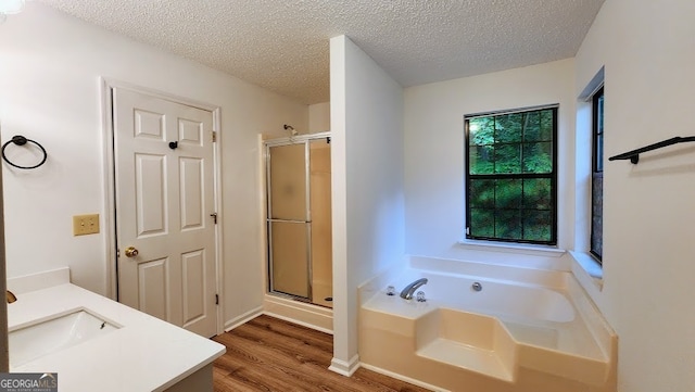 bathroom with vanity, shower with separate bathtub, hardwood / wood-style floors, and a textured ceiling