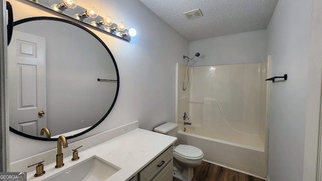 full bathroom featuring vanity, wood-type flooring, a textured ceiling, shower / tub combination, and toilet