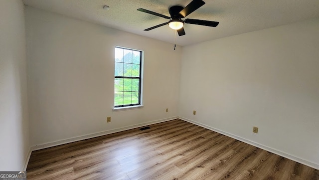 spare room with light wood-type flooring, ceiling fan, and a textured ceiling