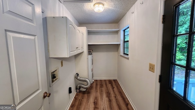 clothes washing area with a textured ceiling, dark wood-type flooring, cabinets, hookup for a washing machine, and water heater