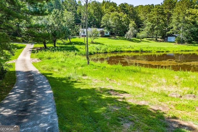 view of community featuring a storage unit, a lawn, and a water view