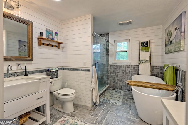 full bathroom featuring plus walk in shower, wood walls, vanity, and toilet