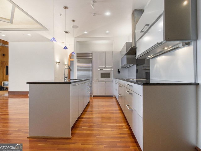 kitchen featuring sink, wall oven, light hardwood / wood-style flooring, an island with sink, and pendant lighting