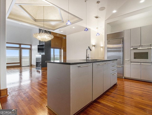 kitchen with pendant lighting, oven, sink, and an island with sink