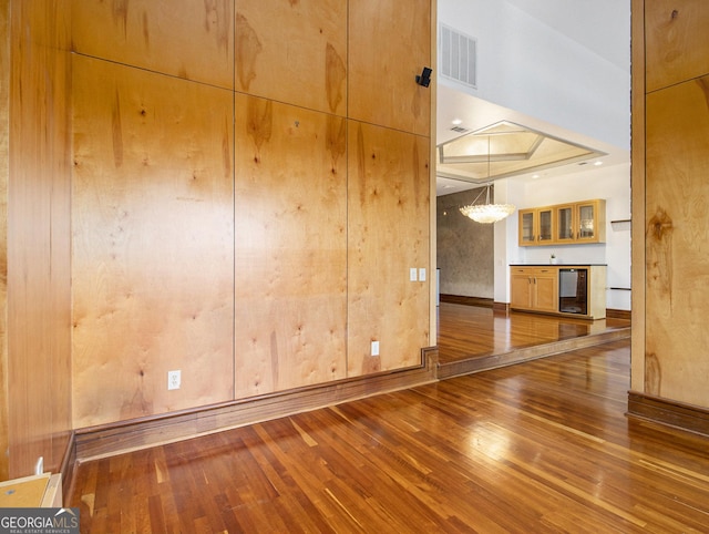 spare room featuring wood-type flooring, a tray ceiling, and beverage cooler