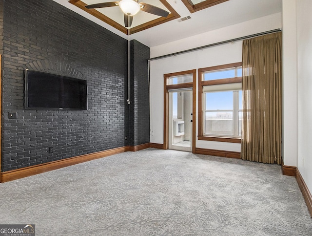 unfurnished living room with carpet, ceiling fan, and brick wall