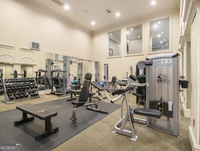 gym with a towering ceiling and crown molding