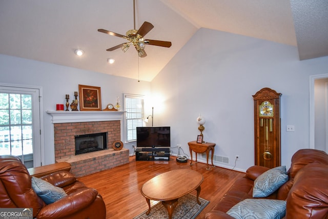 living room featuring ceiling fan, a fireplace, wood-type flooring, and high vaulted ceiling