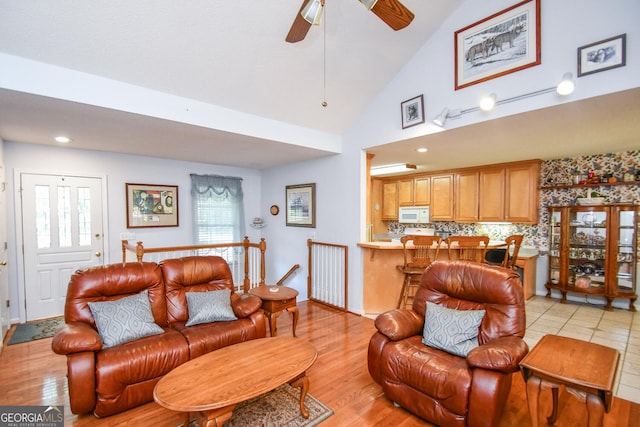 living room featuring light wood-type flooring, ceiling fan, and high vaulted ceiling