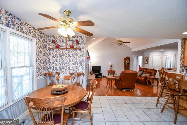 dining area with light wood-type flooring, lofted ceiling, ceiling fan, and a textured ceiling