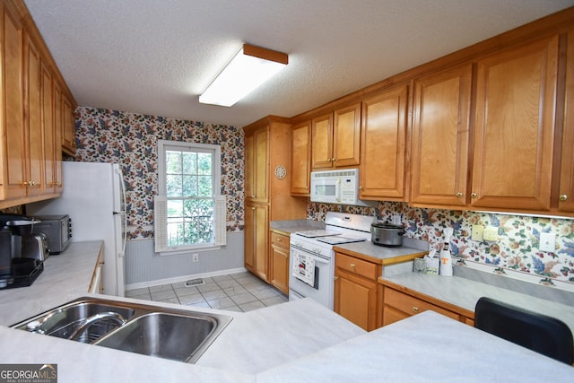 kitchen with light tile patterned floors, a textured ceiling, sink, and white appliances