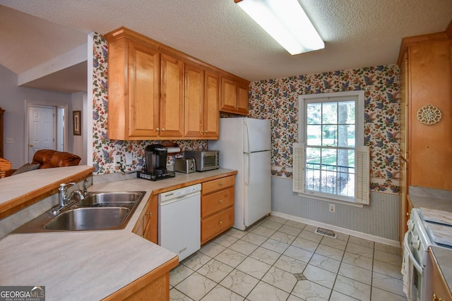 kitchen with white appliances, a textured ceiling, and sink