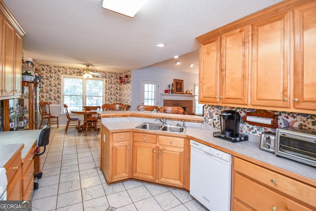 kitchen with a fireplace, kitchen peninsula, white dishwasher, a textured ceiling, and sink