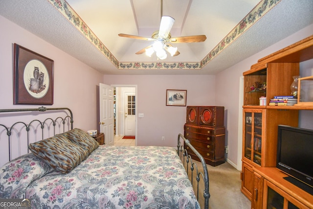 carpeted bedroom featuring a tray ceiling and ceiling fan