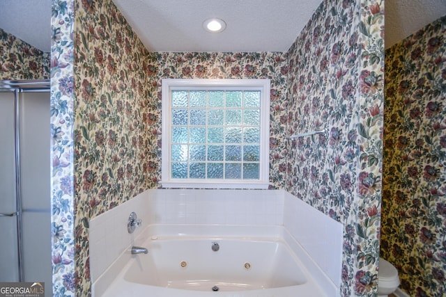 bathroom with a textured ceiling, toilet, and a bath