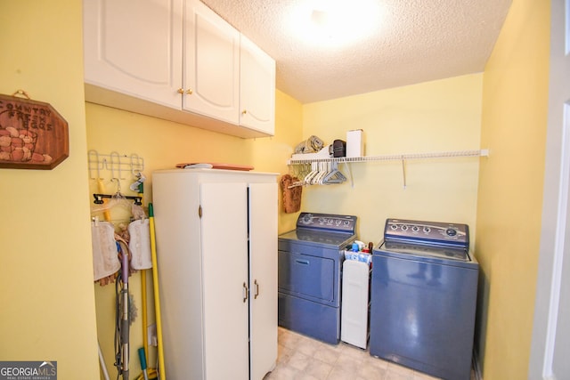 washroom with cabinets, a textured ceiling, and washer and dryer