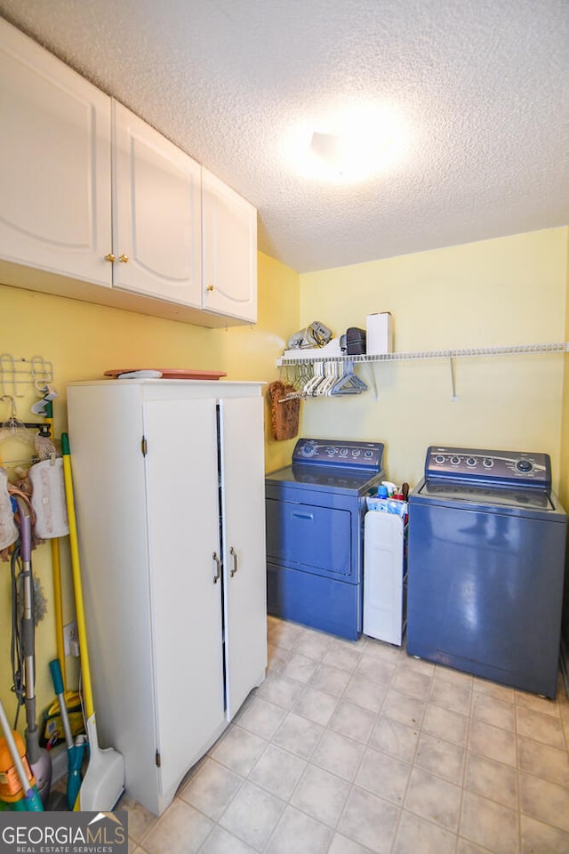 laundry room with cabinets, a textured ceiling, and washer and dryer