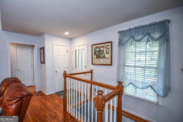 corridor with hardwood / wood-style flooring and a textured ceiling