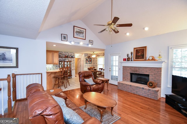 living room with light hardwood / wood-style flooring, ceiling fan, plenty of natural light, and a brick fireplace