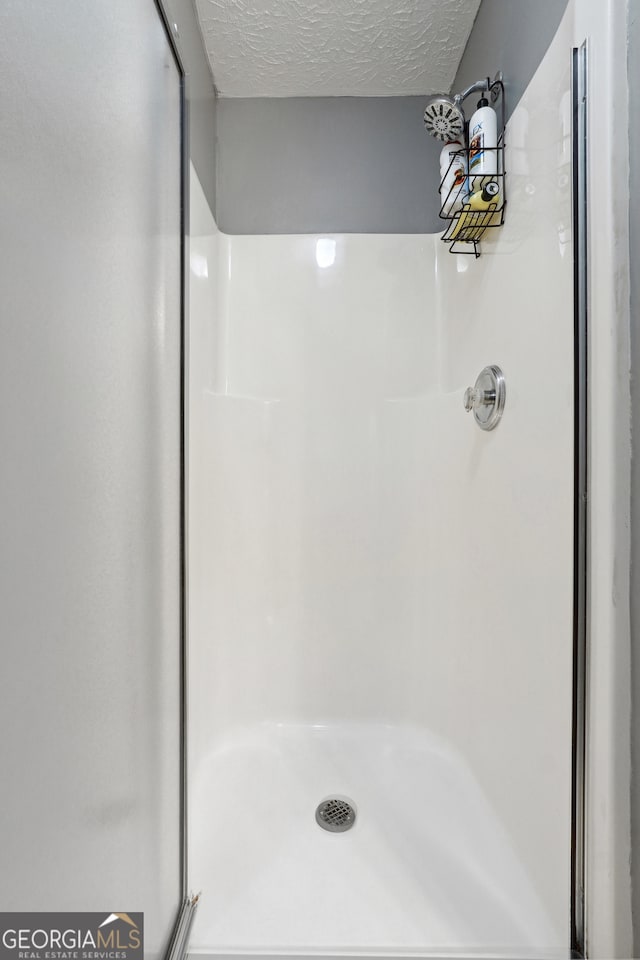 bathroom featuring a textured ceiling and walk in shower