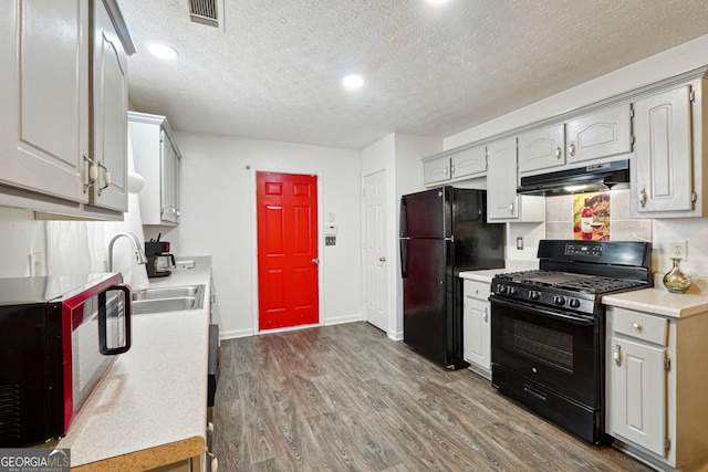 kitchen with a textured ceiling, black appliances, dark hardwood / wood-style flooring, and white cabinets