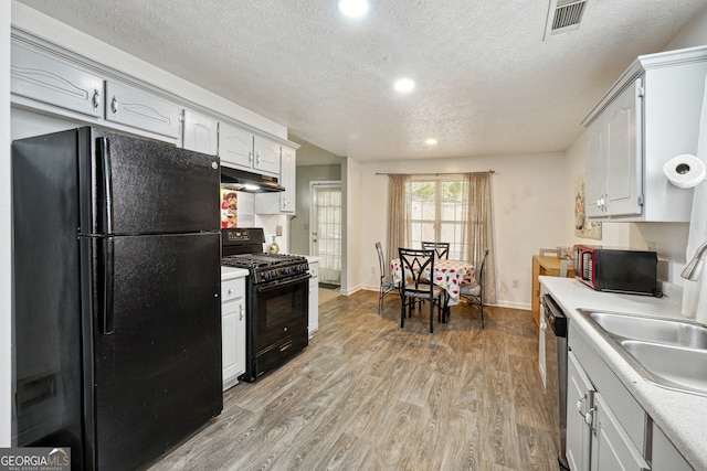 kitchen with sink, a textured ceiling, light hardwood / wood-style flooring, white cabinetry, and black appliances