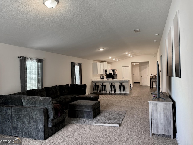 living room with vaulted ceiling, a textured ceiling, and carpet floors