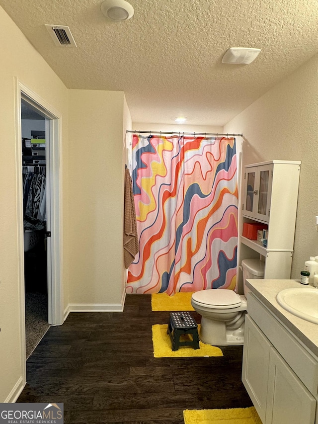 bathroom with vanity, hardwood / wood-style floors, a textured ceiling, a shower with curtain, and toilet