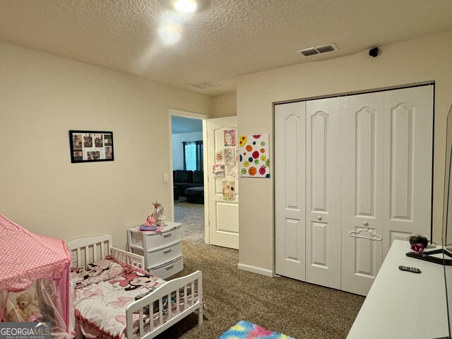 bedroom with a textured ceiling, dark carpet, and a closet