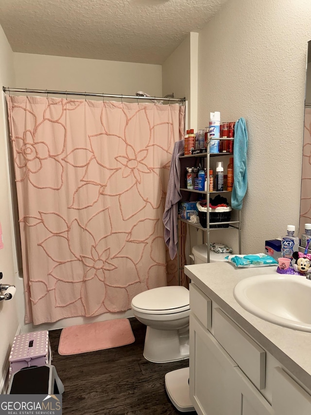 bathroom featuring vanity, a textured ceiling, wood-type flooring, toilet, and a shower with curtain