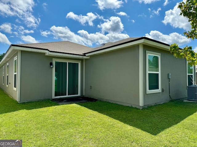 rear view of house featuring central AC unit and a yard