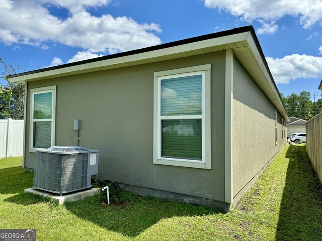 rear view of house featuring a yard and central air condition unit