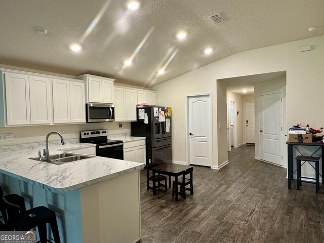 kitchen with sink, white cabinets, vaulted ceiling, kitchen peninsula, and stainless steel appliances