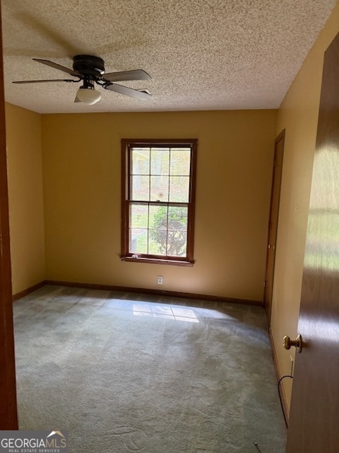 carpeted empty room with ceiling fan and a textured ceiling