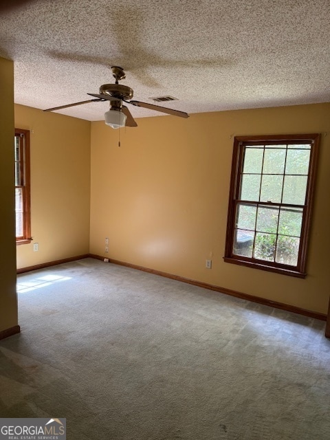 carpeted empty room with ceiling fan and a textured ceiling