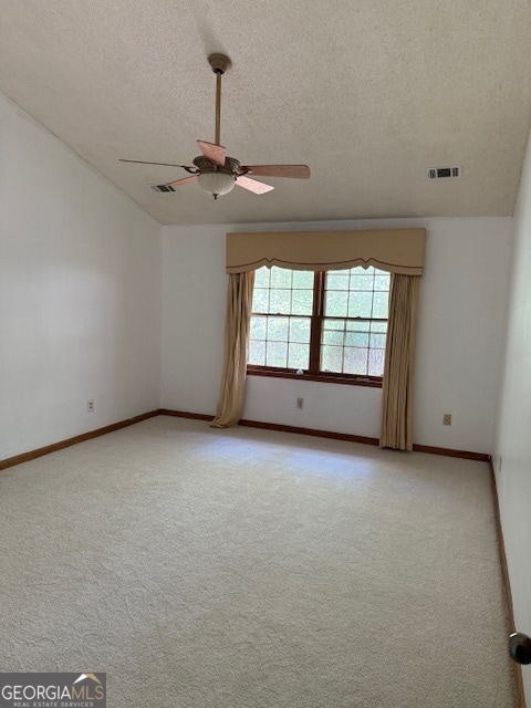 carpeted spare room with lofted ceiling, a textured ceiling, and ceiling fan