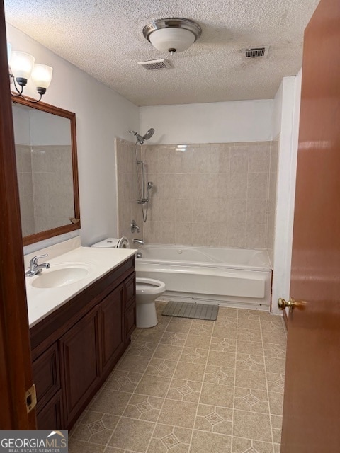 full bathroom with a textured ceiling, tiled shower / bath combo, vanity, and toilet